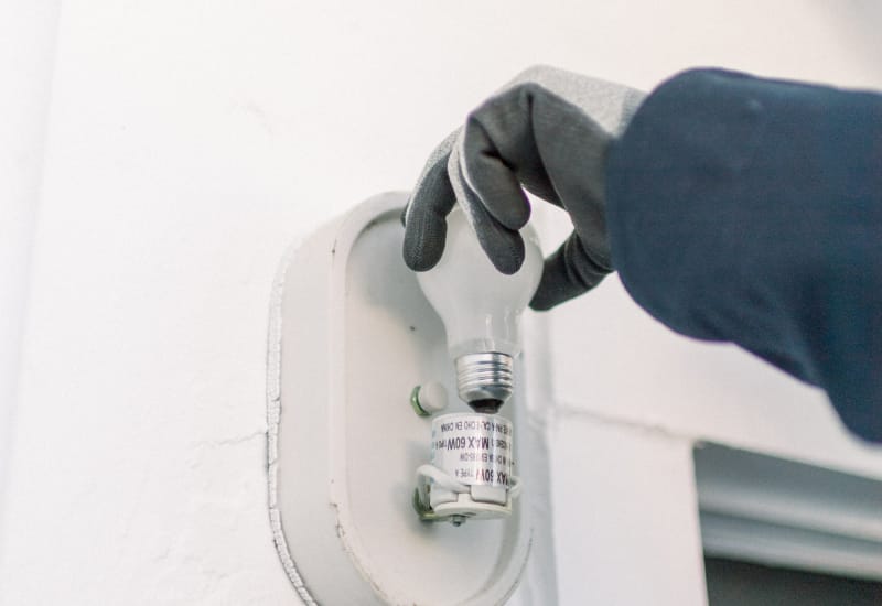 An electrician performing a commercial lighting installation inside an office.